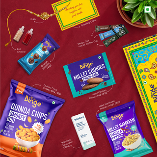 A styled flat-lay collage of multiple packaged snacks and beauty products on a deep red background, including a colorful greeting card, Rakhi Orange laddoo, Coffee Sachet, Millet Cookies, Quinoa Chips, Sunscreen, Roli Chawal, and Millet Namkeen. The products are arranged with callout lines and text labels.